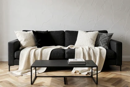 Salon noir et blanc avec canapé en lin anthracite, coussins en velours et boucle, et plaids ivoire tricotés pour un décor confortable et élégant