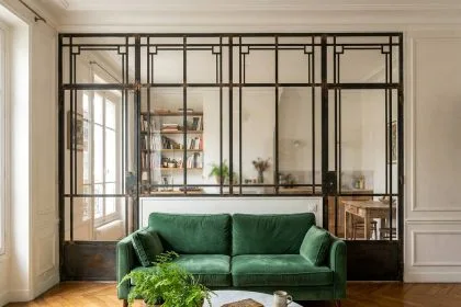 Verrière art déco à petits carreaux géométriques séparant le salon et la cuisine dans un petit appartement parisien avec parquet en point de Hongrie